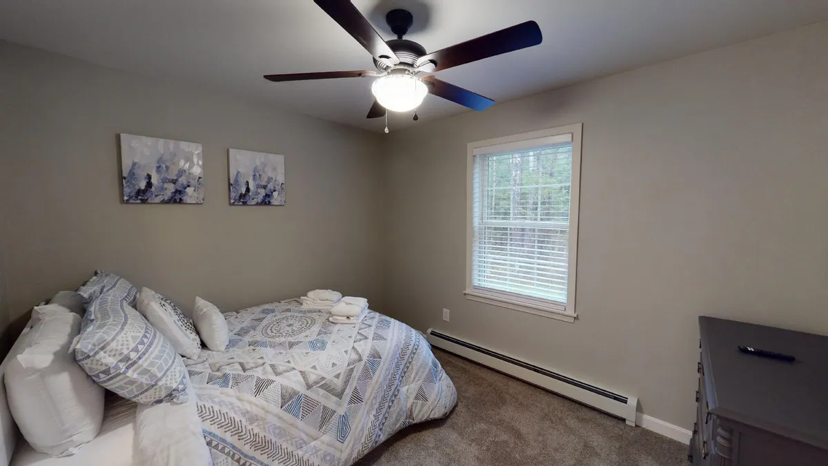 A tranquil bedroom featuring a bed with plush, patterned bedding, a window letting in soft natural light, and abstract wall art. The scene evokes a sense of peace and comfort, perfect for restful nights and relaxed mornings.