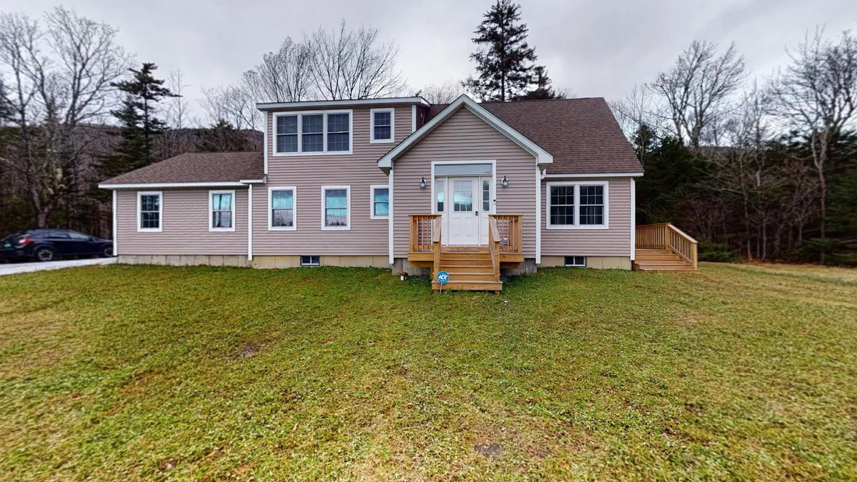 A welcoming exterior shot featuring the front entrance, large windows, and an inviting deck. The scene suggests opportunities for family gatherings or outdoor barbecues, embodying the property’s connection to the outdoors and encouraging exploration beyond the threshold.